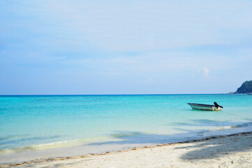 Empty beach with one small boat and calm sea with small ripples and clear skies. Selective focus points.