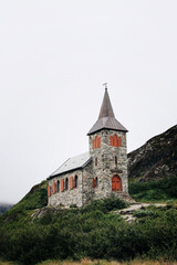 Fototapeta na wymiar Grense Jakobselv. Cloudy morning in small village in Finnmark county on the shore of the Barents Sea on a foggy day. Arctic Northern Norway landscapes. King Oscar II Chapel. Norwegian stone church