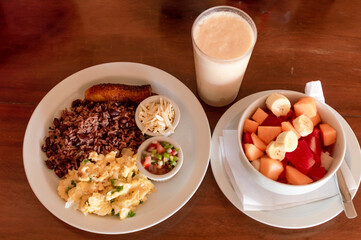 Gallopinto breakfast served on wooden table, gallopinto with fried eggs with pico de gallo on wooden table