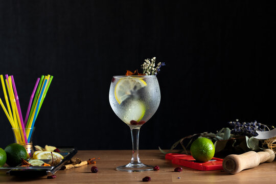 Gin tonic reci&eacute;n preparado y decorado sobre una mesa de madera