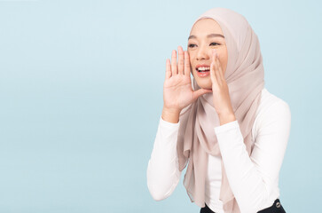 Portrait of islamic woman shouting on blue wall studio. Pretty muslim girl.