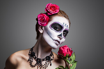 Closeup portrait of a young woman with sugar skull makeup, showing Calavera Catrina. Dia de los...
