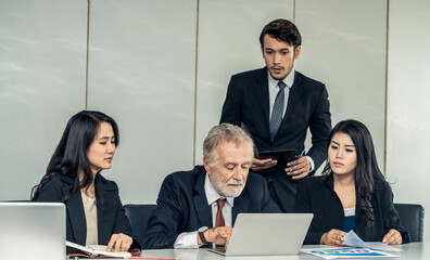 Senior caucasian manager working in office with assistance of young Asian business people and...