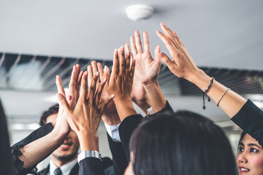 Many Happy Business People Raise Hands Together With Joy And Success. Company Employee Celebrate After Finishing Successful Work Project. Corporate Partnership And Achievement Concept.