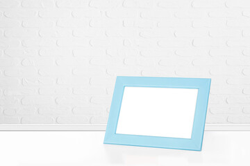Light blue color photo frame at white bricks wall