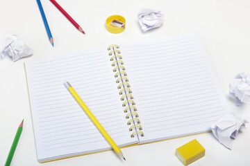 Education concept: notebook with colorful pencils and crumpled paper balls