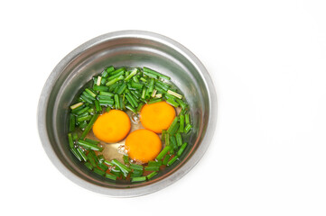 Fresh chicken eggs with onion leaves for cooking isolated on white background.