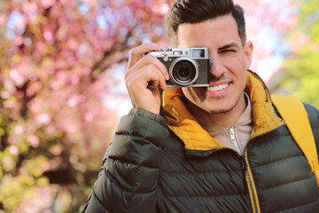 Happy male tourist with camera outdoors on spring day