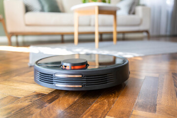 Robot vacuum cleaner on the parquet floor. Cleaning in living room at home
