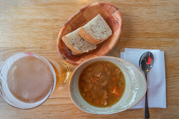 Traditional Icelandic and Scandinavian lamb meat soup with white bread in wooden plate and glass of beer, Iceland, closeup, details.