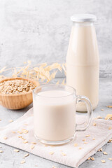 Vegan non dairy alternative milk. Oat milk in the mug on grey stone table background