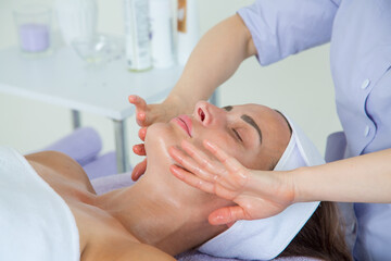 A girl doctor in a lavender-colored suit performs a very beautiful and professional massage of the face of a girl lying on a couch