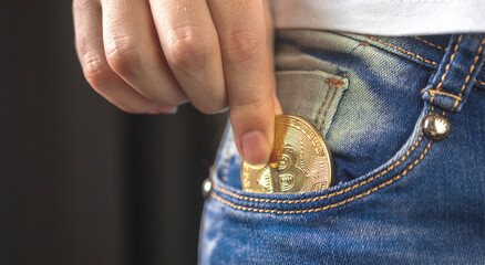 Fototapeta premium Banner woman putting bitcoin in jeans pocket, golden cryptocurrency coin in pocket background photo
