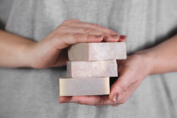 Female hands hold stack of handmade soap.