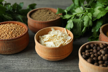Different spices in wooden bowls on gray textured background