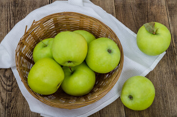 Green apples in a wicker bowl with white napkin