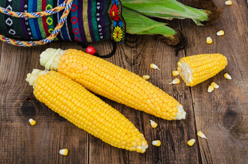 Two cobs of corn without leaves on wooden table