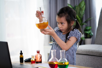 Asian 5 years old asian girl is studying for liquid density science experiment at home for online class in covid-19 pandemic, distance, e learning, new normal education for kid safety from virus.