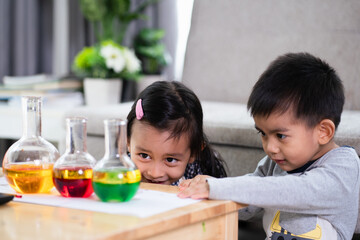 Asian 5 years old student and little brother looking to oil and water separation for liquid density science experimental at home , concept of homeschool, learn through play for kid in the family life.