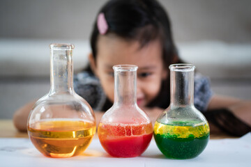 Unidentified 5 years old student is observe the water and oil separation for liquid density easy science experimental at home, homeschool, stem education, self learning for kid in family life. - obrazy, fototapety, plakaty