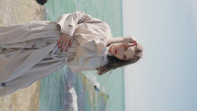 Close up portrait of young woman smiling at camera in wind over ocean. 