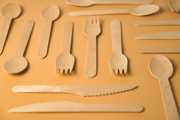 Design of disposable wooden teaspoons on light orange background. Recycling concept.