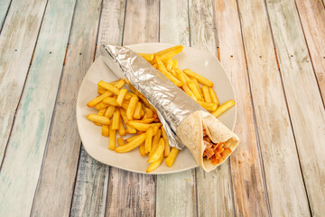 typical durum prepared in a kebab restaurant with a side of french fries and aluminum foil to roll...