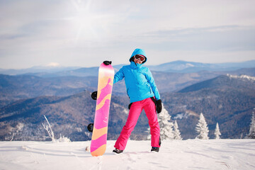 Woman snowboarder poses with board.