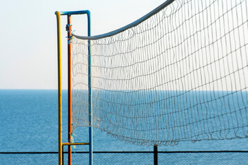 Old volleyball net against a clear blue sky and sea outdoors. The sport playground. Simple concept photography.
