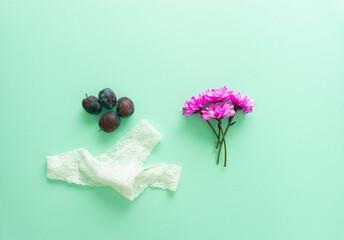 Creative arrangement of plums, white underwear and fresh purple flowers