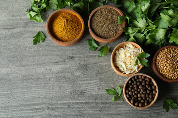 Different spices in wooden bowls on gray textured background