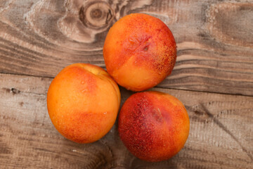 ripe yellow apricots with water drops on brown plank table 