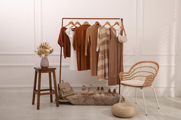 Rack with stylish clothes and shoes in dressing room. Interior design