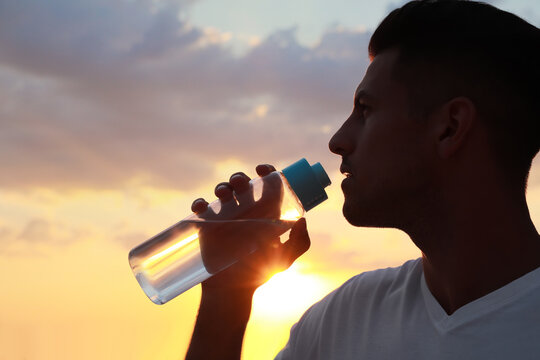 Man Drinking Water To Prevent Heat Stroke Outdoors At Sunset