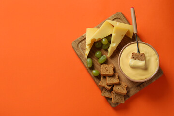 Concept of delicious food with fondue on orange background