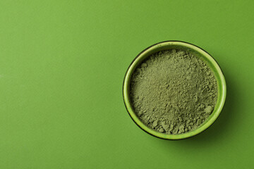 Bowl of matcha powder on green background