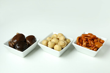 Bowls of marinated mushrooms on white background