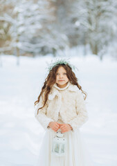 Fototapeta na wymiar Portrait of a serious girl in a wreath in the winter park.