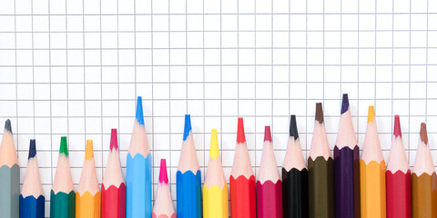 Multicolored pencilson the blank checkered page.