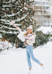 Young woman in winter clothes walks in the park holding a delicate bouquet of dried flowers.