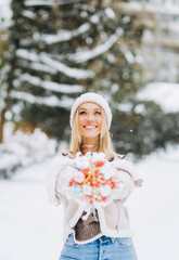 Gorgeous woman with blond hair holding a bouquet of dried flowers in her hands on a background of winter scenery.