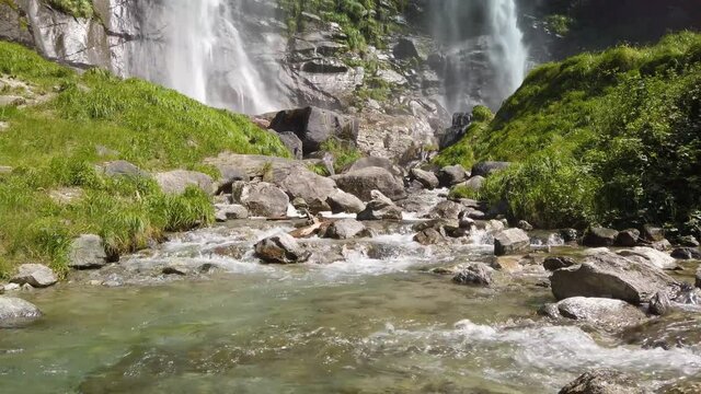 Water stream running from the beautiful Acquafraggia waterfall in Piuro, in the Bregaglia valley in Italy, before the ascent to the Maloja pass. It is a beautiful sunny summer day.