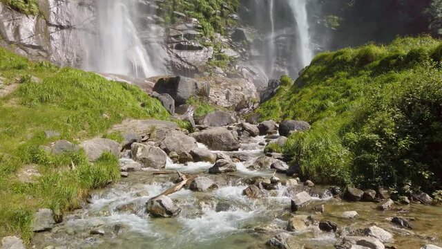 Water stream running from the beautiful Acquafraggia waterfall in Piuro, in the Bregaglia valley in Italy, before the ascent to the Maloja pass. It is a beautiful sunny summer day.
