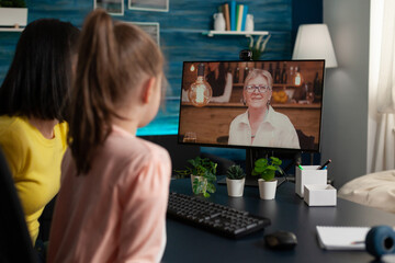 Mother and daughter using video call conference technology for modern communication. Adult and child talking to grandma old lady on online internet connection while sitting at home