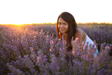 young latin woman looks at camera among lavender flowers at sunset