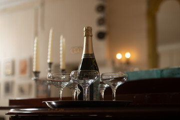 A tray with glasses of champagne and a bottle of sparkling wine.