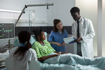 Diverse medical team consulting african american patient about disease infection for healing treatment. Teenager receiving healthcare medicine from doctors of african ethnicity and nurse