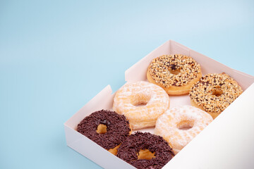 Chocolate donuts, white sugar
and a sprinkling of nuts, on a blue background. 