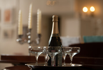 A tray with glasses of champagne and a bottle of sparkling wine.
