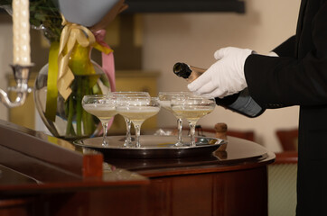 A tray with glasses of champagne and a bottle of sparkling wine.